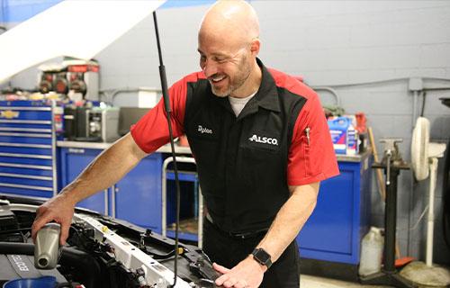 Alsco mechanic changing oil on vehicle